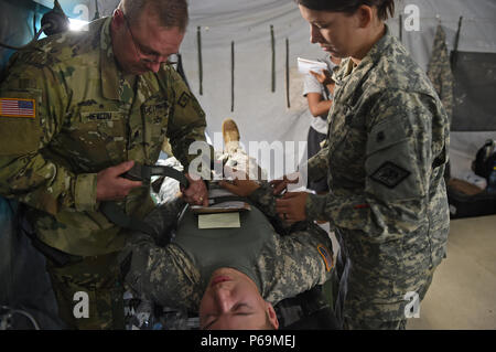 COATEPEQUE, Guatemala - Arkansas National Guard service Mitglieder Oberstleutnant Kevin Newcom, Links, Arkansas medizinische Befehl erweiterte Praxis eingetragene Krankenschwester, und SPC. Tara Bell, rechts, 296Th Boden Ambulance Medical Unternehmen Medic, Riemen aus einem simulierten verletzten Soldaten entfernen während einer medizinischen Bereitschaft übung, 26. Mai 2016, während der Übung über den Horizont 2016 GUATEMALA. Arkansas National Guard SPC. Cameron Chailland, Innenstadtkirchen statt Vorwärts Support Unternehmen Lader und Maschinist, spielte die Rolle eines Patienten, während medizinische Fachleute für reale Situationen geübt. (U.S. Air Force Foto von Senior Stockfoto