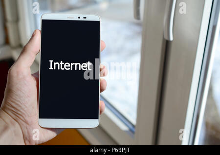 Ein Mensch sieht, ein weißer Aufschrift auf einem BlackBerry-Smartphone angezeigt werden, den er in seiner Hand hält. Internet. Stockfoto