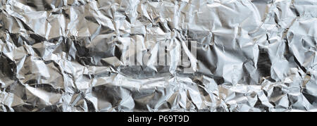 Dünne zerknittertes Blatt zerdrückt Zinn Aluminium silber Folie Hintergrund mit glänzenden zerknitterten Oberfläche für Textur. Stockfoto