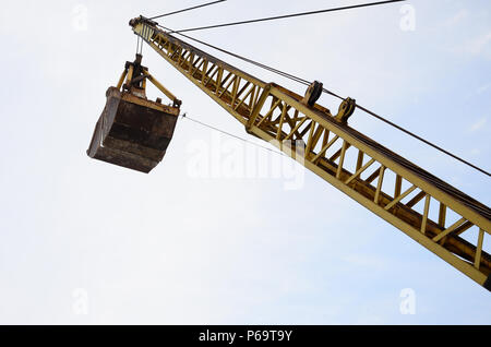 Alte gelbe mechanische Greifer Greifer auf blauen Himmel Hintergrund. Stockfoto