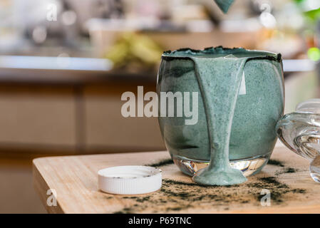 Detailansicht frischen Kefir probiotik Drink in Klarglas mit grünen spirulina Pulver auf Küche Tabelle gemischt. Stockfoto