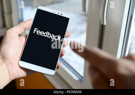 Ein Mensch sieht, ein weißer Aufschrift auf einem BlackBerry-Smartphone angezeigt werden, den er in seiner Hand hält. Feedback. Stockfoto