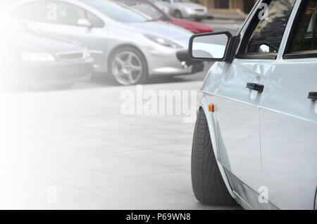 Diagonale Ansicht einer weiß-glänzend Auto, die auf einem Quadrat von grauen Fliesen steht. Stockfoto