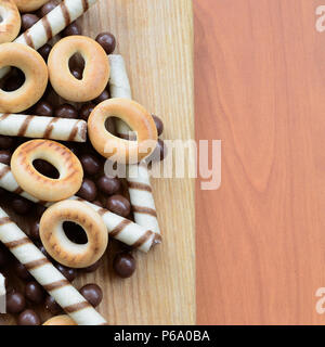 Knusprige Tubuli, Schokolade schmelzen Kugeln und Bagels liegen auf einem Holz- Oberfläche. Mix aus verschiedenen Süßigkeiten. Stockfoto