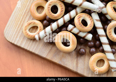 Knusprige Tubuli, Schokolade schmelzen Kugeln und Bagels liegen auf einem Holz- Oberfläche. Mix aus verschiedenen Süßigkeiten. Stockfoto