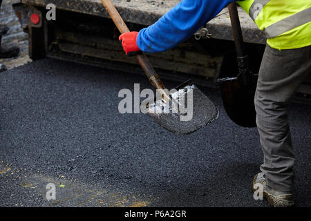 Arbeitnehmer, die Asphalt fertiger Maschine beim Straßenbau. Stockfoto