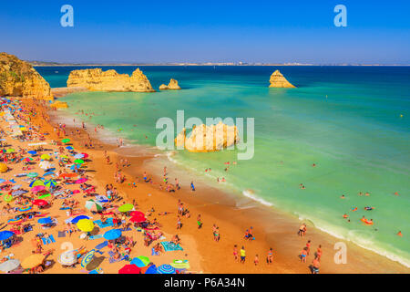 Lagos, Portugal - 21 August 2017: viele Menschen Sonnenbaden und genießen unter bunten Sonnenschirmen auf der beliebten Praia Dona Ana. Sommer Urlaub in der Algarve, Portugal. Stockfoto