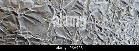 Dünne zerknittertes Blatt zerdrückt Zinn Aluminium silber Folie Hintergrund mit glänzenden zerknitterten Oberfläche für Textur. Stockfoto