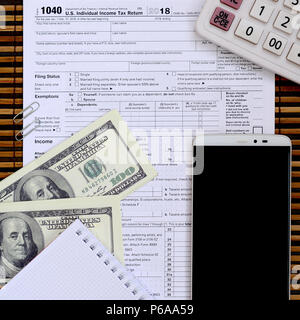 Zusammensetzung der Elemente liegen auf dem 1040 Steuerformular. Dollarscheine, Rechner, Smartphone, Büroklammer und Notepad. Die Zeit, die Steuern zu bezahlen. Stockfoto