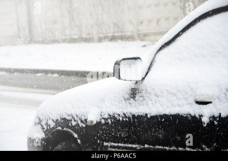 Fragment der Auto unter einer Schicht von Schnee Nach schwere Schneefälle. Die Karosserie ist mit weißen Schnee bedeckt. Stockfoto