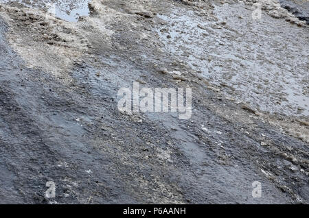 Beschädigte asphaltierte Straße mit Schlaglöchern durch Gefrieren und Auftauen im Winter. Schlechte Straßen. Stockfoto