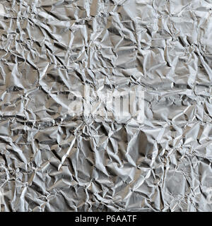 Dünne zerknittertes Blatt zerdrückt Zinn Aluminium silber Folie Hintergrund mit glänzenden zerknitterten Oberfläche für Textur. Stockfoto