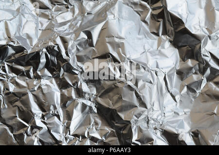 Dünne zerknittertes Blatt zerdrückt Zinn Aluminium silber Folie Hintergrund mit glänzenden zerknitterten Oberfläche für Textur. Stockfoto