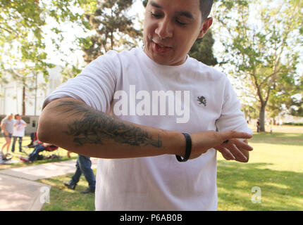 Pensionierte Armee SPC. Geoffrey G. Quevedo zeigt eine seiner Tattoos gewitzelt, dass es ihm "einen Arm und ein Bein", bei der Enthüllung des Denkmals zu Ehren unserer gefallenen Wand Mai 30 in Long Beach, Kalifornien, das Bonmot ist teilweise wahr für ehemalige 10 Mountain Division Kavallerie Scout; er die meisten seiner linken Arm und Bein verloren zu einer improvisierten explosiven Gerät blast in Kandahar, Afghanistan im Jahr 2011. Nur wenige Tage vor dem Knall, fast behauptete Quevedo, Fellow 10 Mountain Division Soldaten Pfc. Theodore B. Hetzen unter ähnlichen Bedingungen getötet wurde. (U.S. Armee Foto von Sgt. 1. Klasse Alexandra Hays, 201St Pre Stockfoto