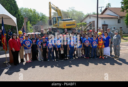 Laredo, Strafverfolger, fünftes Sortierer, Gemeindeleiter und Texas Nationalgarde posieren für ein Gruppenfoto, während ein Texas Army National Guard Soldat demoliert ein Haus in Laredo, Texas, 4. Mai 2016. Die Texas National Guard gemeinsame Counterdrug Taskforce abgerissen etwa 27 Strukturen in Laredo, die von Drogenkonsumenten und Händlern verwendet wurden, als Teil der Task force Betrieb Durchgreifen. (U.S. Air National Guard Foto von 1 Lt Alicia Lacy/Freigegeben) Stockfoto