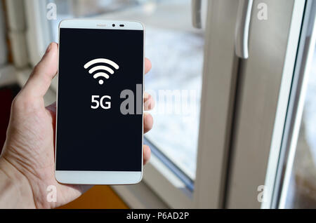Ein Mensch sieht, ein weißer Aufschrift auf einem BlackBerry-Smartphone angezeigt werden, den er in seiner Hand hält. 5 G. Stockfoto