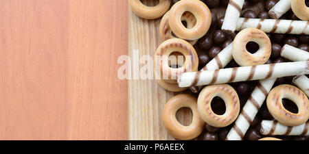 Knusprige Tubuli, Schokolade schmelzen Kugeln und Bagels liegen auf einem Holz- Oberfläche. Mix aus verschiedenen Süßigkeiten. Stockfoto