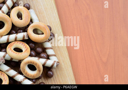 Knusprige Tubuli, Schokolade schmelzen Kugeln und Bagels liegen auf einem Holz- Oberfläche. Mix aus verschiedenen Süßigkeiten. Stockfoto