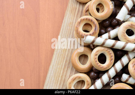 Knusprige Tubuli, Schokolade schmelzen Kugeln und Bagels liegen auf einem Holz- Oberfläche. Mix aus verschiedenen Süßigkeiten. Stockfoto