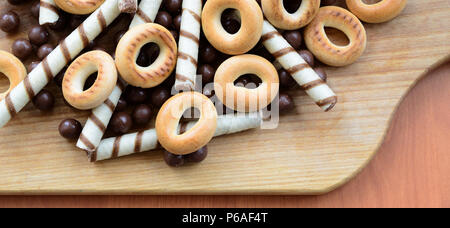 Knusprige Tubuli, Schokolade schmelzen Kugeln und Bagels liegen auf einem Holz- Oberfläche. Mix aus verschiedenen Süßigkeiten. Stockfoto