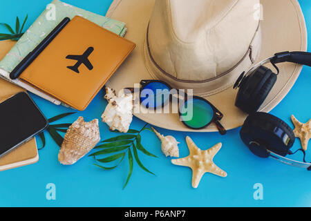 Elegante schwarze Telefon, Reisepass, Sonnenbrille, Karte, Hut, Kopfhörer, Muscheln, Notebook am trendigen blau Papier. Flach. Planung sommer urlaub Konzept. tr Stockfoto