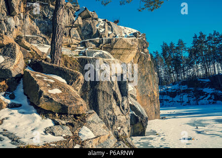 Winter Natur. Granit Rocky gefrorenen See. Granitsteinbruch an einem sonnigen Tag Stockfoto