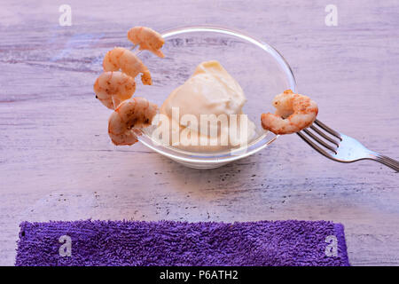 Shot-Glass Garnelen mit Sauce Tartar - einfach Cocktail Rezept für festliche Partei, auf weissem Teller mit Löffel auf alten weißen Holz- Tabelle, Ansicht von oben Stockfoto