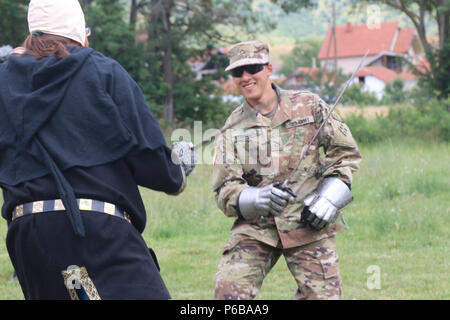 GRAČANICA, Kosovo - Soldaten der multinationalen Battle Group - Osten verbrachte den Tag in der Dritten Internationale Festival der mittelalterlichen Kunst und Handwerk - Schild, auf dem Hof des Königs Milutin Volksschule in Gračanica, Kosovo, am 23. Juni. Pfc. Isaac Rodriguez mit Bandit Truppe, 3.Staffel, 61 Cavalry Regiment, 2 Infantry Brigade Combat Team, 4 Infanterie Division, erhält Anweisung von einem lokalen Gračanica Sword Master at arms. (US Army Foto von Sgt. Casey Hustin, 19 Public Affairs Abteilung) Stockfoto