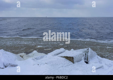 Schiff am Horizont klicken Sie auf das Meer im Winter vor dem Hintergrund der Dunklen blauen Wellen in der Nähe des gefrorenen Ufer im Schnee Stockfoto