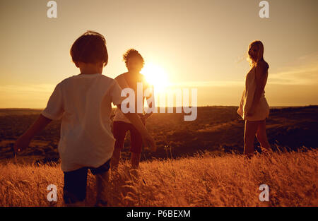 Glückliche Familie Spaß spielen bei Sonnenuntergang auf die Natur. Stockfoto