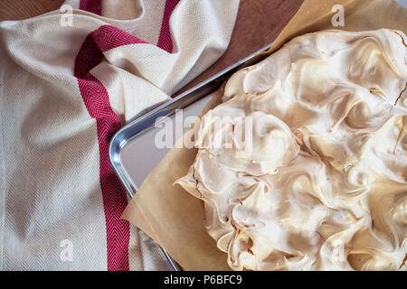 Kochen der Baiser Basis für eine Pavlova Dessert. Frische Baiser, mit Strahlend goldene Spitze, auf Backpapier und eine Edelstahl Backform. Overhea Stockfoto