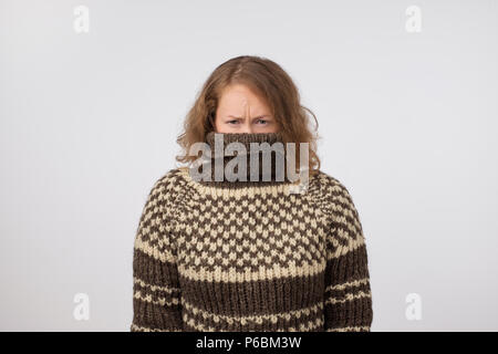 Frau in warmen Braun Pullover ihr Gesicht verstecken. Nur die Augen gesehen. Sie möchte anonym bleiben. Angst vor Menschen und soziale Phobie Stockfoto