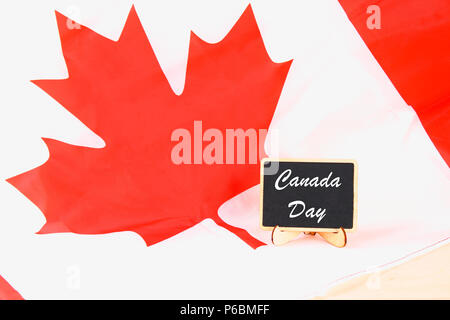 Schiefertafel mit dem Wort Happy Canada Day auf der Nationalflagge. Fest der 1. Juli Stockfoto
