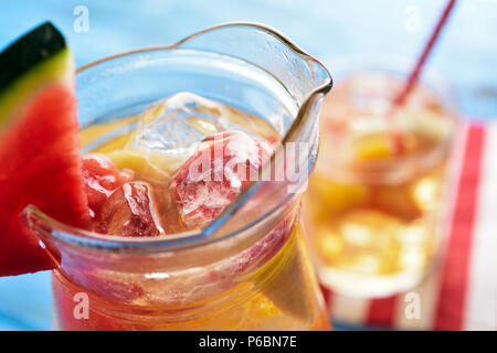 Nahaufnahme von einem Glas Krug mit erfrischenden spanische Sangria Blanca, weiße Sangria, mit frischem Obst, eine blaue, rustikalen Holztisch Stockfoto