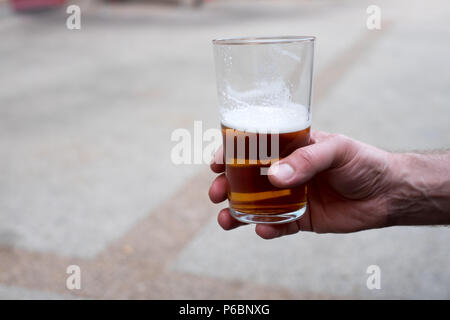 Eine männliche Hand mit einem Pint cask Ale/Handwerk Bier Stockfoto
