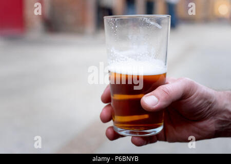 Eine männliche Hand mit einem Pint cask Ale/Handwerk Bier Stockfoto