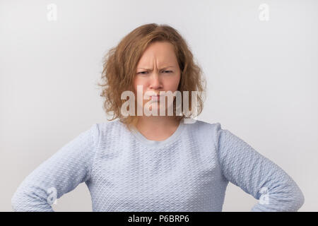 Porträt einer jungen und wütende Frau in Blau Pullover auf grauem Hintergrund. Sie ist nicht mit den Ergebnissen zufrieden. Sein verärgert auf Ehemann oder Freund Stockfoto