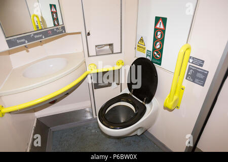 eisenbahntoilette/Toilette - mit nassem Boden, der benutzt wird und ein wenig schmutzig ist - mit behindertengerechtem Zugang und Bars und Waschbecken im britischen Zug in der Nähe von SW London. GROSSBRITANNIEN. Stockfoto