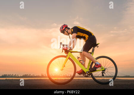 Road bike Radfahrer Mann, Radfahren. Radfahren Sport Fitness Athleten Reiten Fahrrad auf offener Straße bis zum Sonnenuntergang. Stockfoto