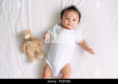 Porträt eines crawling Baby auf dem Bett in Ihrem Zimmer, adorable Baby boy in Weiß sonnig Schlafzimmer, ein neugeborenes Kind entspannen im Bett, Kindergarten für junge CHILDRE Stockfoto