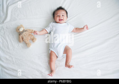 Porträt eines crawling Baby auf dem Bett in Ihrem Zimmer, adorable Baby boy in Weiß sonnig Schlafzimmer, ein neugeborenes Kind entspannen im Bett, Kindergarten für junge CHILDRE Stockfoto