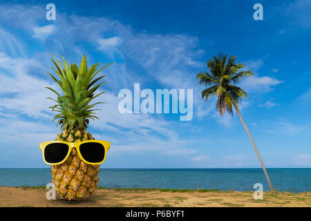 Tropischer Sommer Köstlichkeiten, frische Ananas am Strand, Mode hipster Ananas, hellen Sommer Farbe, tropische Früchte mit Sonnenbrille, kreative Kunst Stockfoto