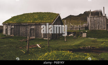 Alte Wikingerdorf in Island mit foggy Hill. Alte hölzerne Gebäude bedeckte Gras Stockfoto