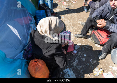 Ein flüchtling Mutter hält Ihr Kind, während sie wartet, in der Nähe der Grenze Tor der Grenze am provisorischen Flüchtlingslager der Greek-Macedonian borde zu überqueren Stockfoto