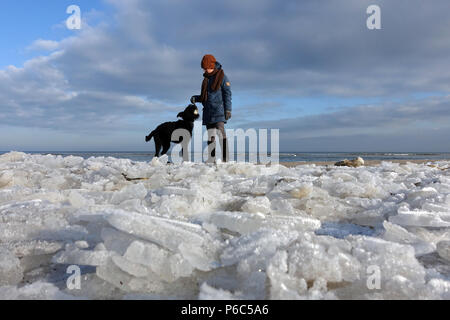 Ahlbeck, Deutschland, Frau spielen mit Ihrem Hund im Winter am Strand Stockfoto