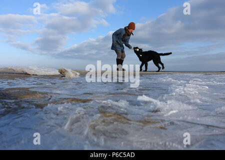 Ahlbeck, Deutschland, Frau spielen mit Ihrem Hund im Winter am Strand Stockfoto