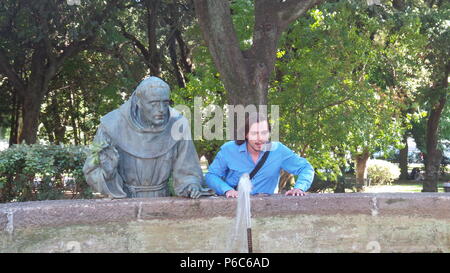 Eine Person, die neben einer Statue ein gut beobachten stehend Stockfoto