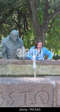 Eine Person, die neben einer Statue ein gut beobachten stehend Stockfoto