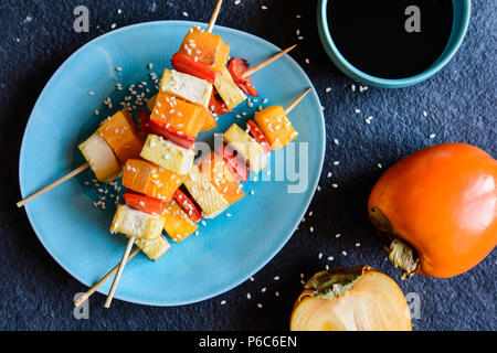 Vegetarische Spieße mit Persimonen, Tofu, Käse, Paprika, Sesam und serviert mit Sojasoße Stockfoto