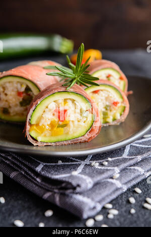 Gebratene Zucchini gefüllt mit Reis, Käse, Paprika und Schinken in Schichten gewickelt Stockfoto